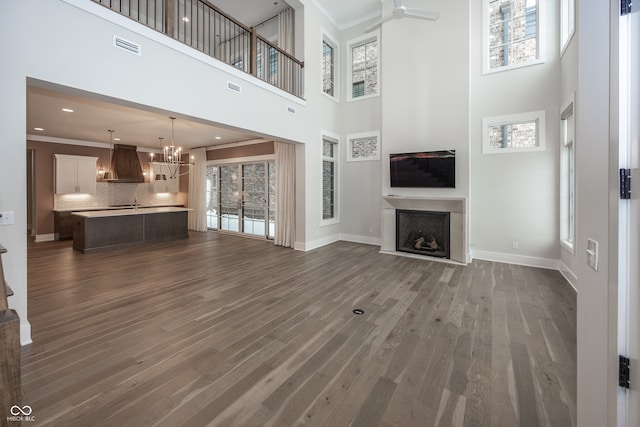 unfurnished living room featuring a high ceiling, a wealth of natural light, and crown molding