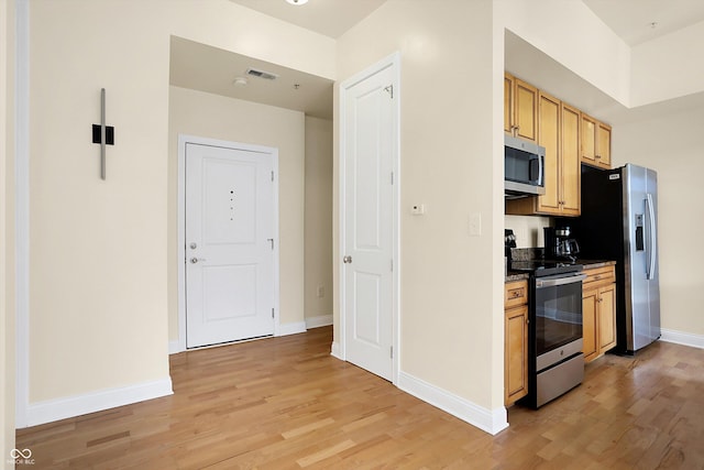 kitchen featuring stainless steel appliances, light brown cabinetry, and light hardwood / wood-style flooring