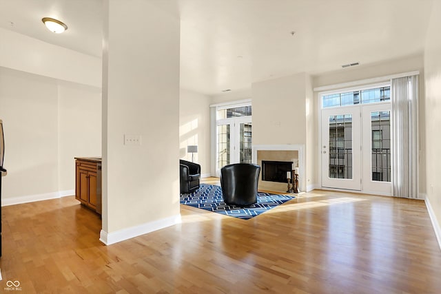 unfurnished living room featuring french doors, a healthy amount of sunlight, and light hardwood / wood-style floors