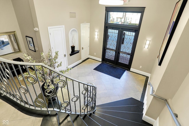 entryway featuring french doors, a towering ceiling, and light tile patterned flooring