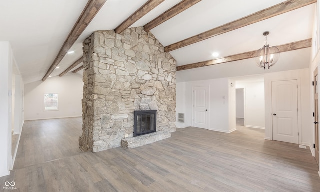 unfurnished living room with hardwood / wood-style floors, vaulted ceiling with beams, a stone fireplace, and an inviting chandelier