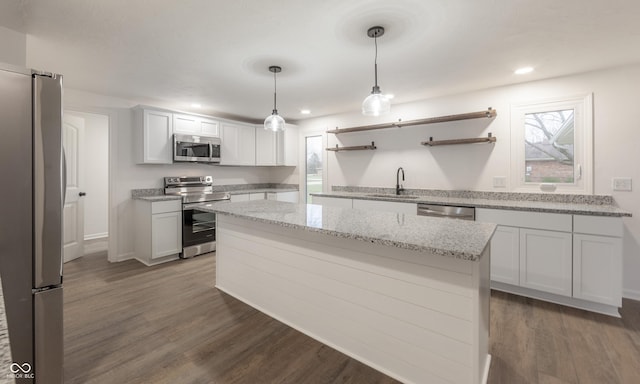 kitchen with hanging light fixtures, sink, appliances with stainless steel finishes, a kitchen island, and white cabinetry