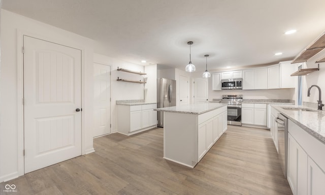 kitchen with white cabinets, hanging light fixtures, sink, appliances with stainless steel finishes, and light stone counters