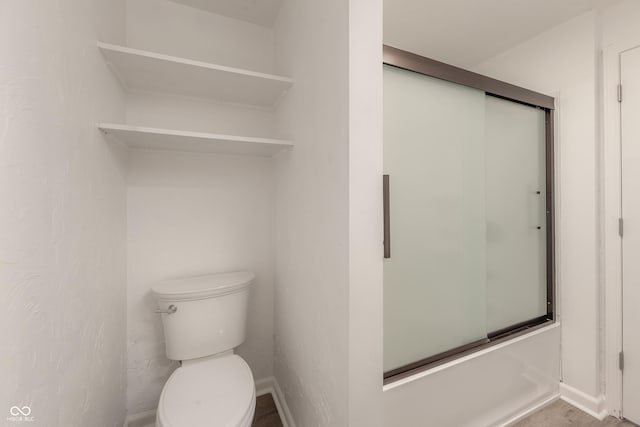 bathroom with toilet and bath / shower combo with glass door