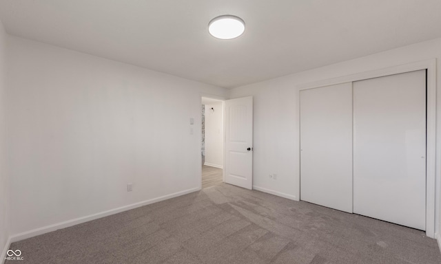 unfurnished bedroom with light carpet and a closet