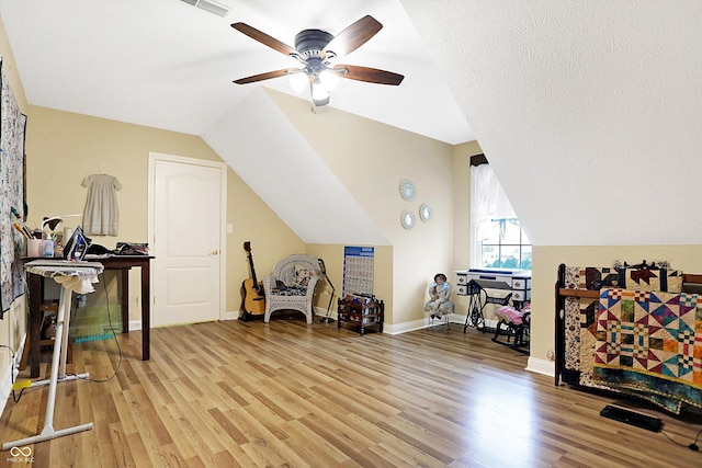 interior space with vaulted ceiling, ceiling fan, wood-type flooring, and a textured ceiling