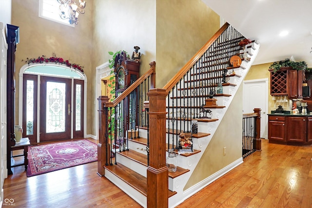 entryway with a chandelier, a towering ceiling, and light hardwood / wood-style flooring