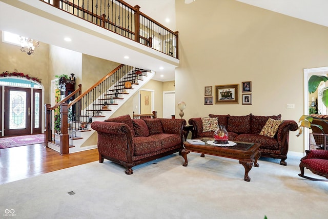 living room featuring a chandelier, a towering ceiling, and hardwood / wood-style flooring