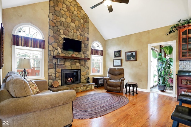 living room with a fireplace, light hardwood / wood-style floors, high vaulted ceiling, and a healthy amount of sunlight