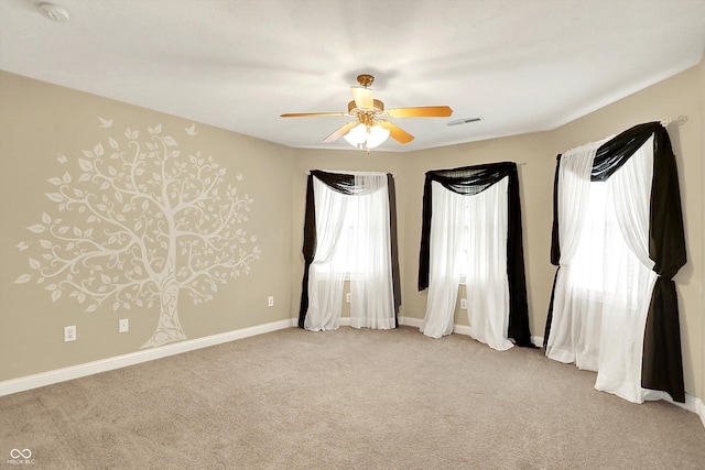 unfurnished room with ceiling fan, visible vents, light carpet, and baseboards