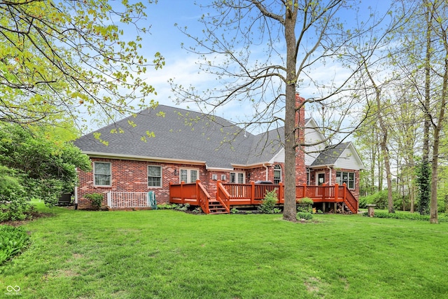 rear view of house featuring a lawn, a wooden deck, roof with shingles, and brick siding