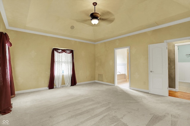 carpeted spare room featuring baseboards, a ceiling fan, a raised ceiling, and ornamental molding