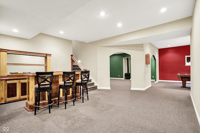 bar featuring bar, arched walkways, baseboards, carpet floors, and recessed lighting