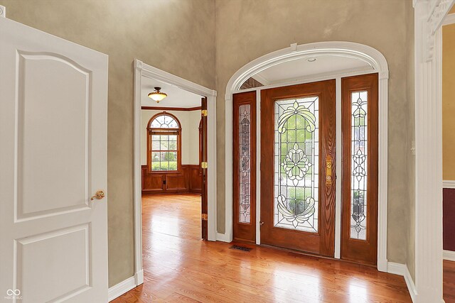 entrance foyer featuring light wood-type flooring, a wainscoted wall, and visible vents
