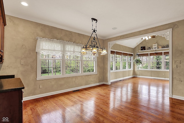 unfurnished dining area featuring crown molding, visible vents, wood finished floors, baseboards, and vaulted ceiling