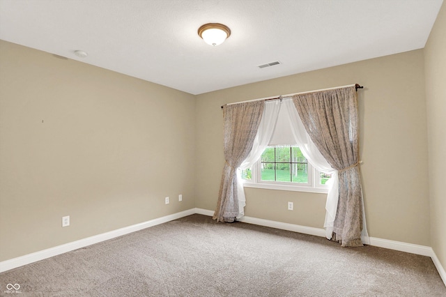 carpeted empty room featuring baseboards and visible vents