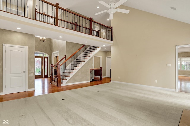 unfurnished living room featuring carpet flooring, a ceiling fan, and high vaulted ceiling