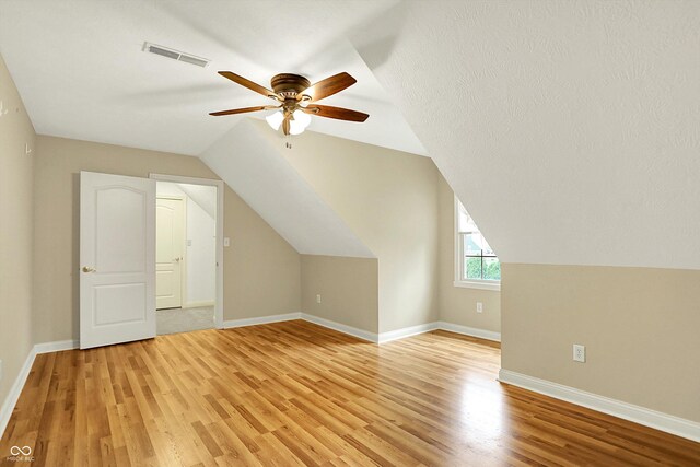 bonus room with visible vents, lofted ceiling, baseboards, light wood-style floors, and ceiling fan