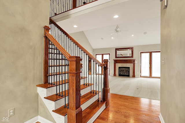 stairway with a fireplace with flush hearth, baseboards, plenty of natural light, and a ceiling fan