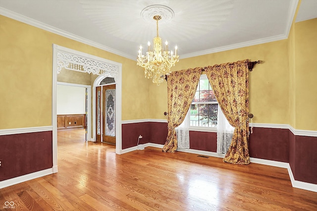 unfurnished dining area featuring arched walkways, a notable chandelier, wood finished floors, and visible vents