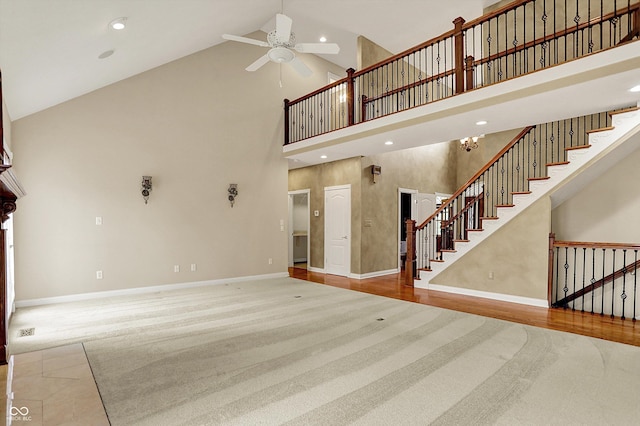 unfurnished living room featuring baseboards, high vaulted ceiling, ceiling fan, and carpet