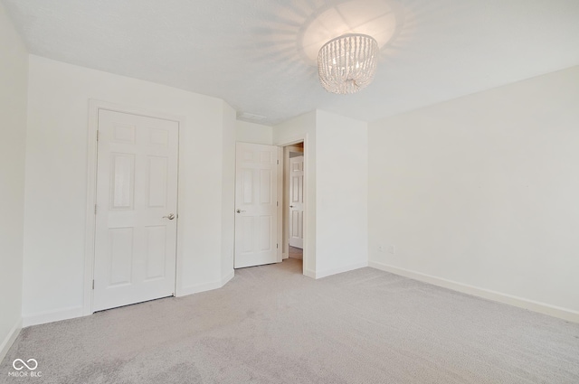 unfurnished bedroom with light carpet and a chandelier