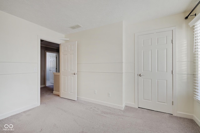 unfurnished bedroom with light colored carpet and a textured ceiling