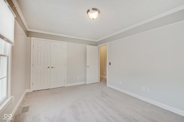 unfurnished bedroom with multiple windows, crown molding, and a closet