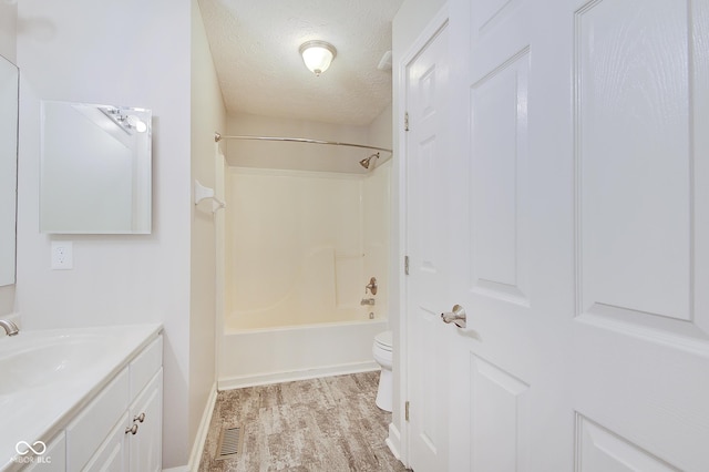 full bathroom featuring bathtub / shower combination, vanity, a textured ceiling, wood-type flooring, and toilet