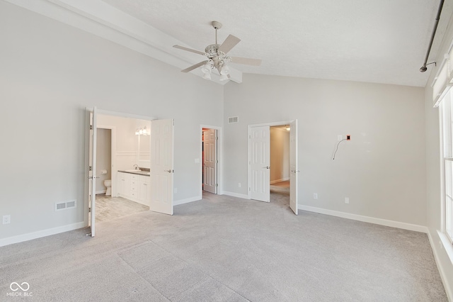 unfurnished bedroom with light carpet, ceiling fan, sink, high vaulted ceiling, and connected bathroom