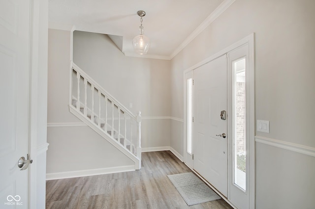 entrance foyer featuring hardwood / wood-style flooring, plenty of natural light, and ornamental molding