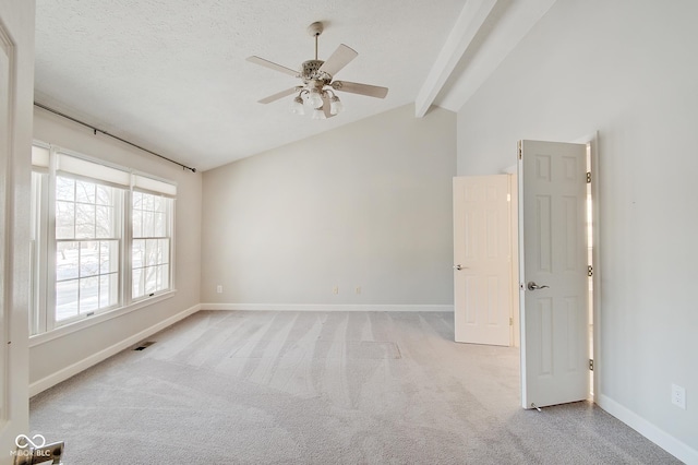 empty room with ceiling fan, light colored carpet, lofted ceiling with beams, and a textured ceiling