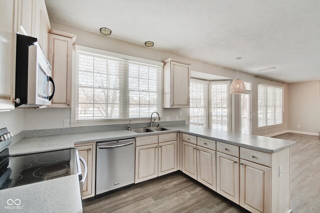 kitchen with sink, dishwasher, kitchen peninsula, pendant lighting, and range