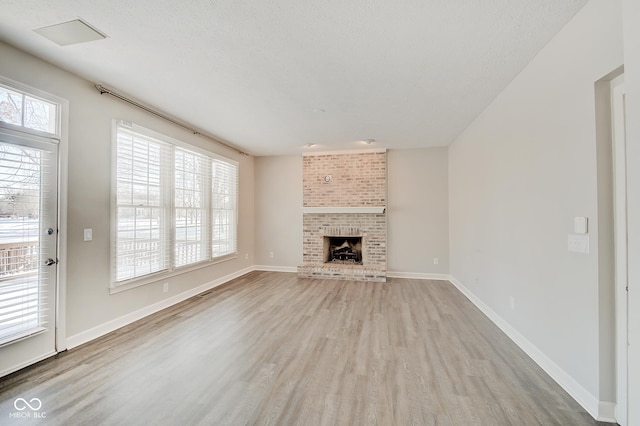 unfurnished living room featuring a fireplace, light hardwood / wood-style floors, and a textured ceiling