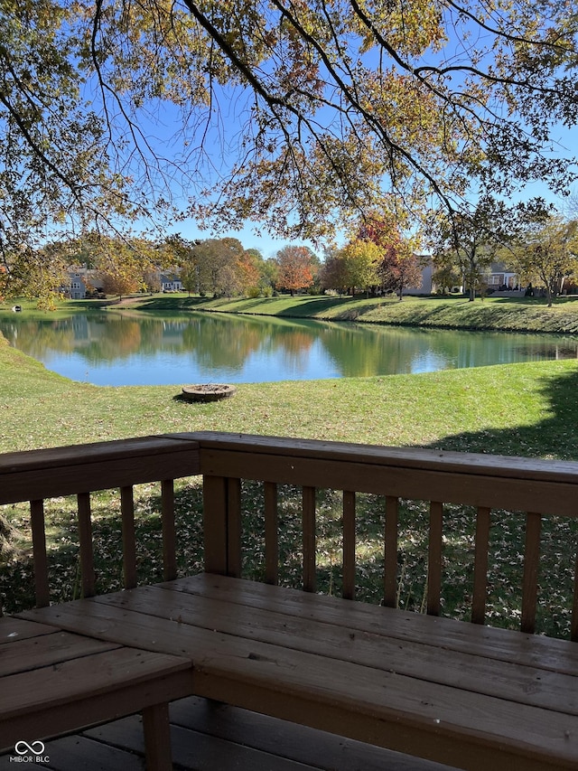 wooden terrace featuring a water view and a lawn