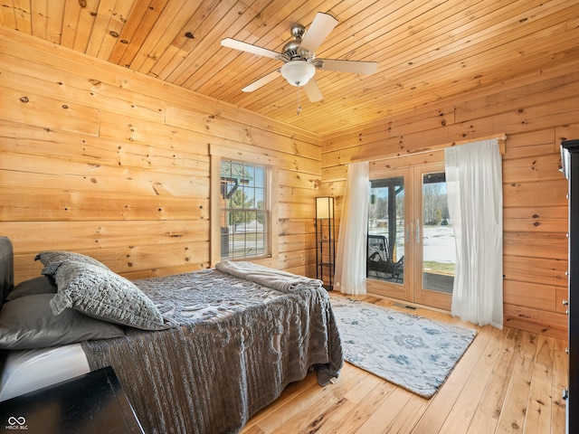 bedroom with wood ceiling, ceiling fan, multiple windows, access to exterior, and wooden walls