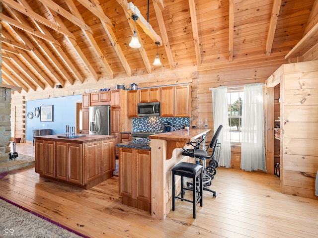 kitchen featuring wood ceiling, appliances with stainless steel finishes, beam ceiling, and kitchen peninsula