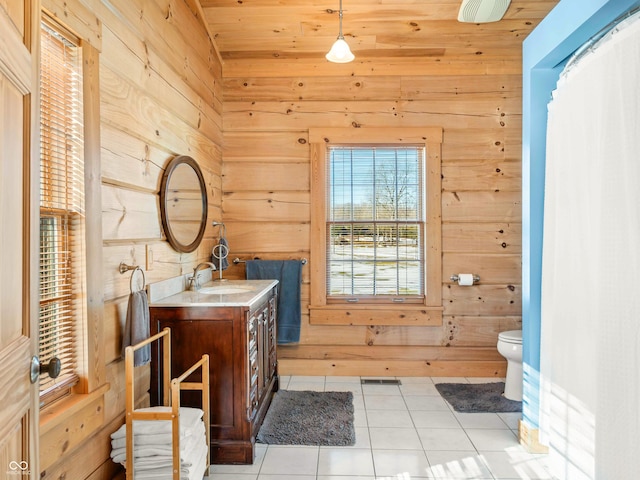 bathroom featuring tile patterned flooring, vanity, wooden walls, and toilet