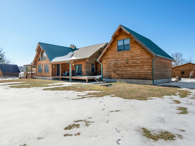 snow covered rear of property with covered porch