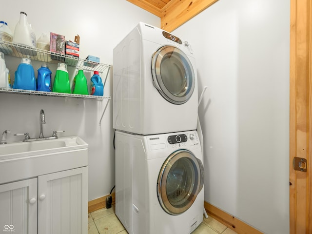 washroom with light tile patterned flooring, stacked washer and dryer, and sink