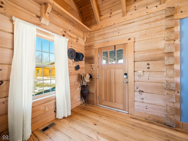 entrance foyer with lofted ceiling with beams, hardwood / wood-style floors, wooden ceiling, and wooden walls