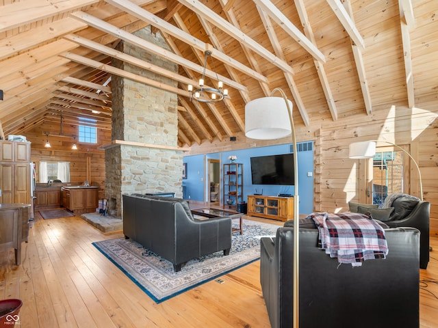 living room with high vaulted ceiling, wood walls, beamed ceiling, wood ceiling, and light hardwood / wood-style flooring