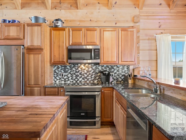 kitchen featuring sink, tasteful backsplash, dark stone countertops, beamed ceiling, and stainless steel appliances