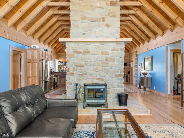 living room with light hardwood / wood-style flooring, high vaulted ceiling, beamed ceiling, and a wood stove