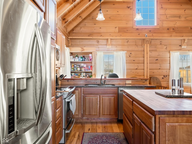 kitchen with appliances with stainless steel finishes, wooden walls, and sink