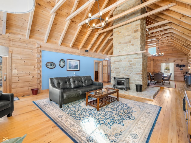 living room featuring a wood stove, a notable chandelier, high vaulted ceiling, and wood walls