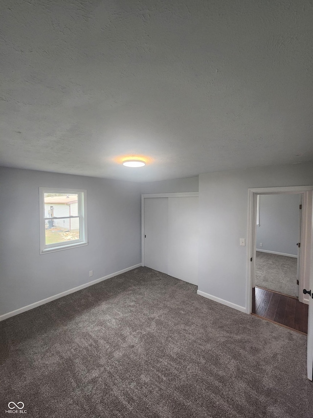 unfurnished room with a textured ceiling and dark carpet