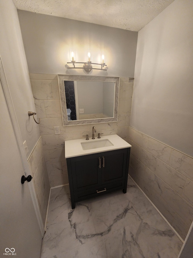 bathroom featuring tile walls, vanity, and a textured ceiling