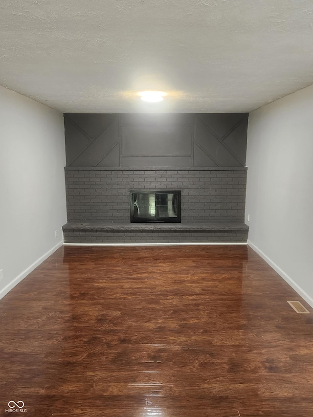 unfurnished living room with a textured ceiling and dark hardwood / wood-style floors