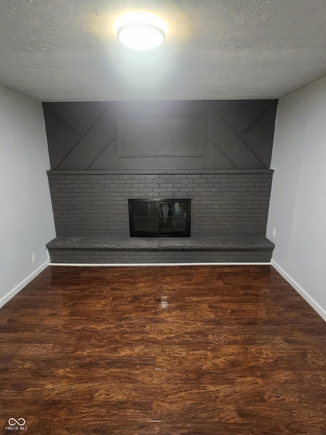 unfurnished living room featuring dark wood-type flooring and a textured ceiling